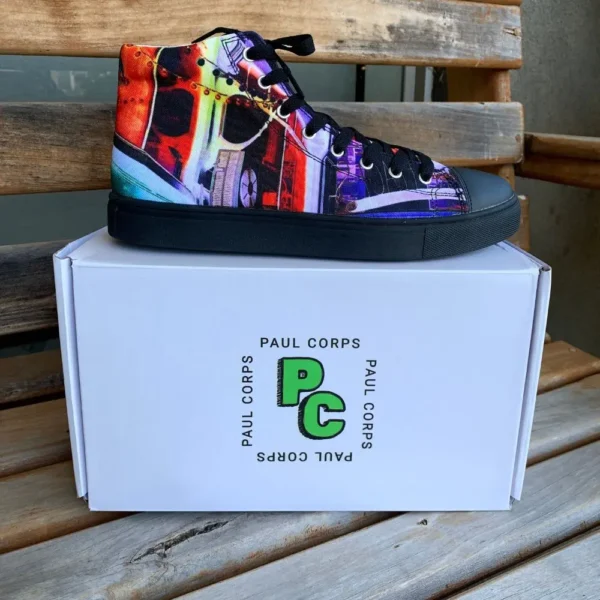 Paul Corps custom printed high-top canvas shoe featuring a vibrant, abstract cityscape design in bold colors with black laces and sole. With Shoe on top of Branded Paul Corps Shoe Box