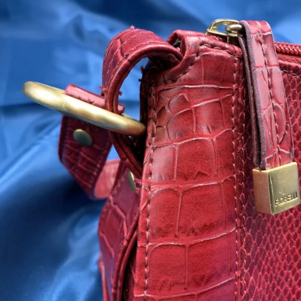 Vintage Fiorelli red shoulder bag with faux croc and snakeskin texture, gold-tone hardware, and zip closure, displayed on a blue satin background.