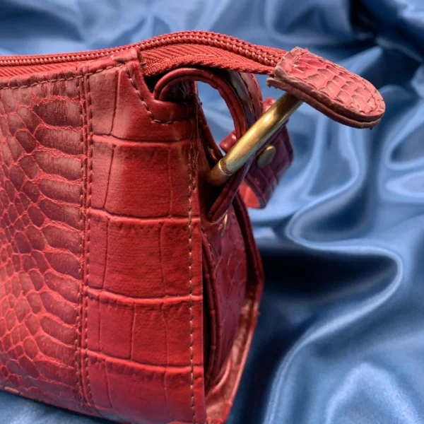 Vintage Fiorelli red shoulder bag with faux croc and snakeskin texture, gold-tone hardware, and zip closure, displayed on a blue satin background.