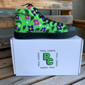 A pair of vibrant green high-top canvas shoes with a colorful floral pattern, black laces, and black soles, displayed on top of a white box labeled "Paul Corps."