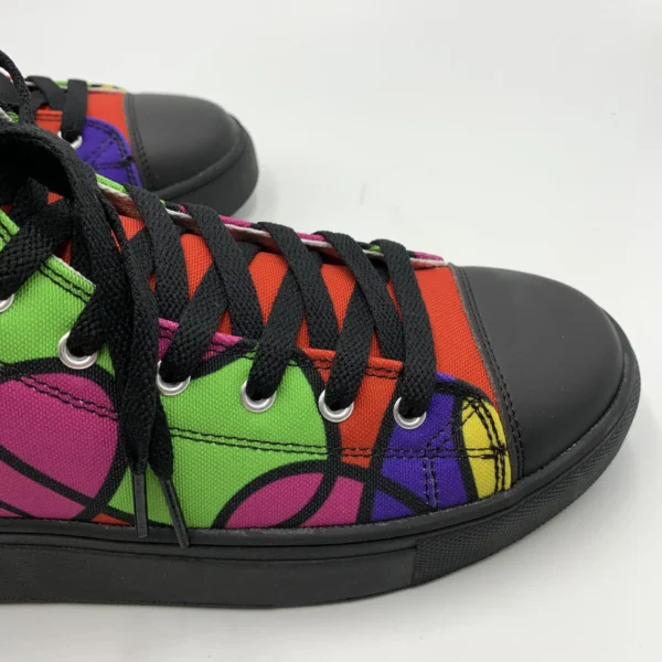 Side close-up of a Lava Lamp Memories high-top canvas shoe by Paul Corps, highlighting the multicolored abstract pattern, black laces, silver eyelets, and black toe cap.