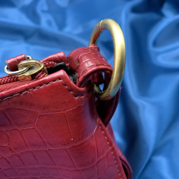 Vintage Fiorelli red shoulder bag with faux croc and snakeskin texture, gold-tone hardware, and zip closure, displayed on a blue satin background.