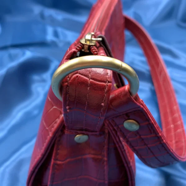 Vintage Fiorelli red shoulder bag with faux croc and snakeskin texture, gold-tone hardware, and zip closure, displayed on a blue satin background.