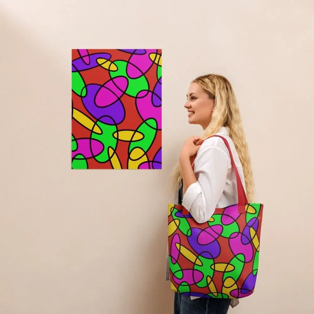 A person wearing a Lava Lamp Memories all-over print tote bag with red handles over their shoulder, standing in front of a matching abstract art print on a beige wall