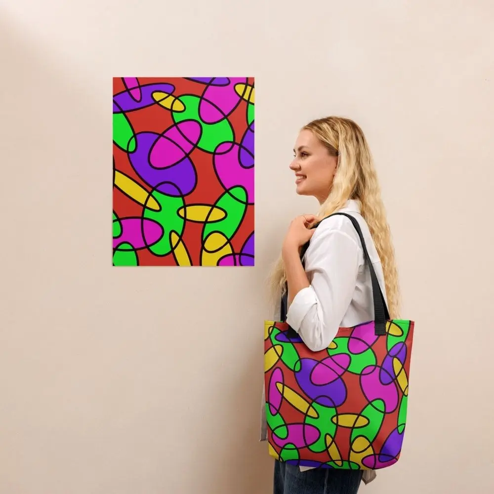 A person wearing a Lava Lamp Memories all-over print tote bag with black handles over their shoulder, standing in front of a matching abstract art print on a beige wall