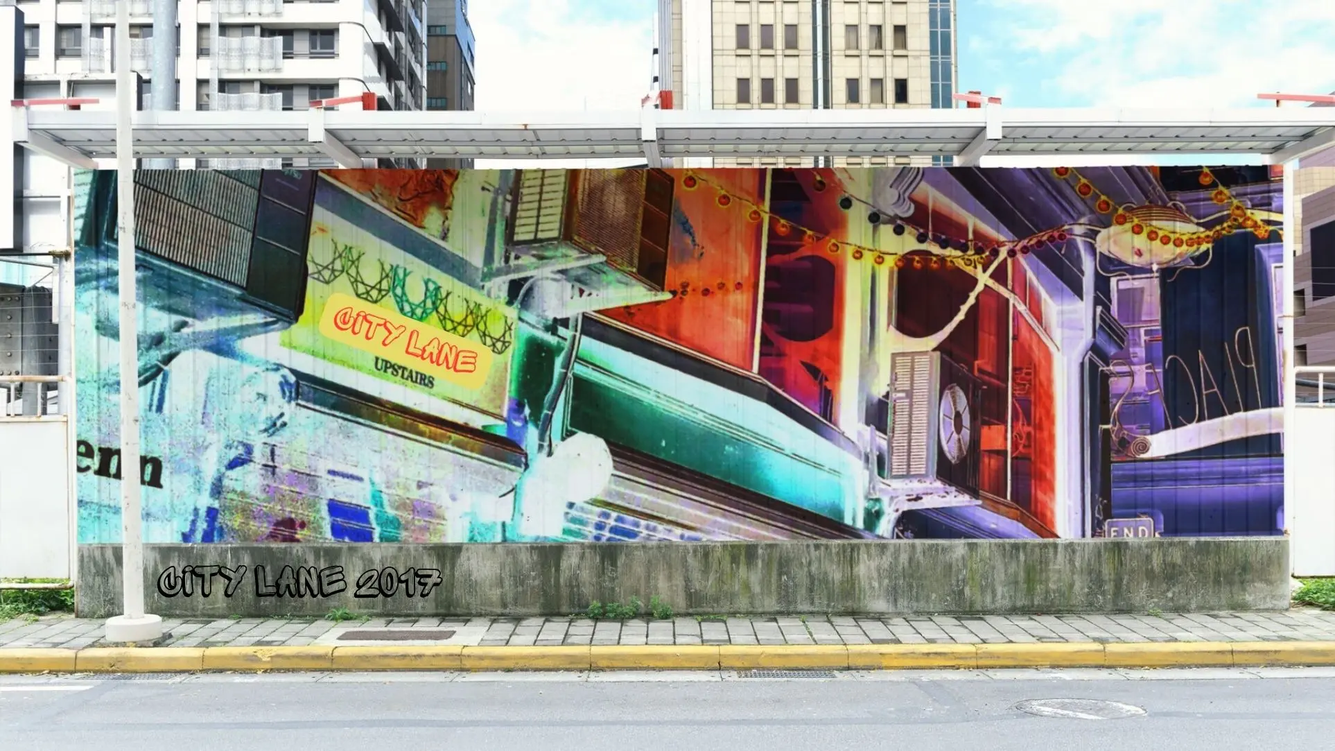 A vibrant urban mural titled "CITY LANE 2017" by Paul Corps, featuring a colourful, abstract cityscape with neon signage, air conditioners, and string lights, painted on a large wall in a city street setting.
