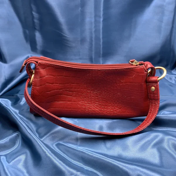 Vintage Fiorelli red shoulder bag with faux croc and snakeskin texture, gold-tone hardware, and zip closure, displayed on a blue satin background.