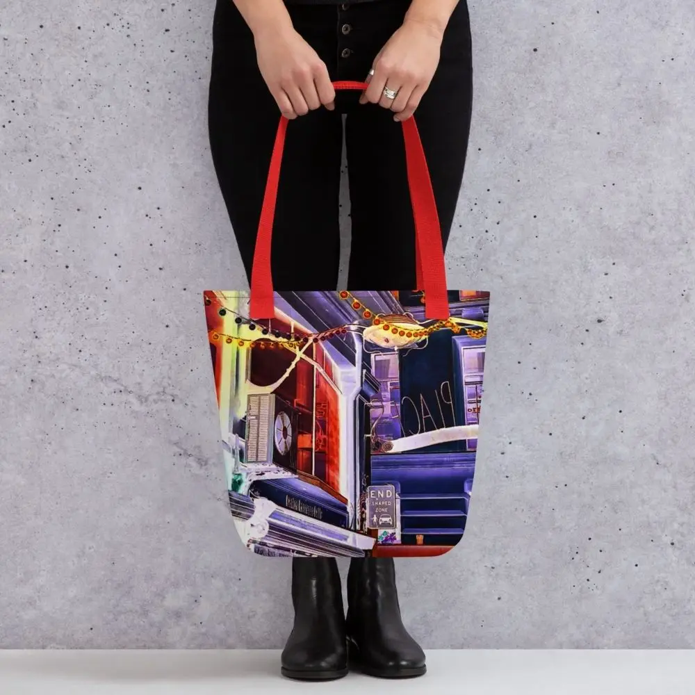A Paul Corps tote bag featuring a vibrant, digitally enhanced photograph of a Melbourne laneway. The design includes colorful string lights, urban signage, and architectural details in shades of purple, orange, and blue, with black handles.