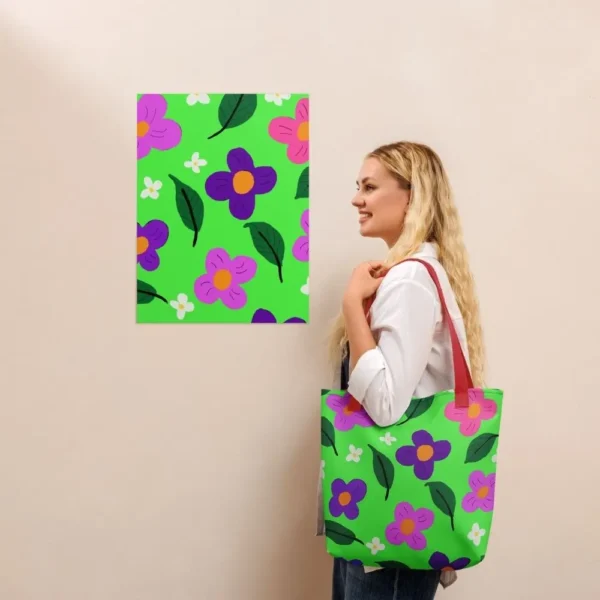 A person wearing a Green Spring all-over print tote bag with red handles over their shoulder, standing in front of a matching an art print on a beige wall
