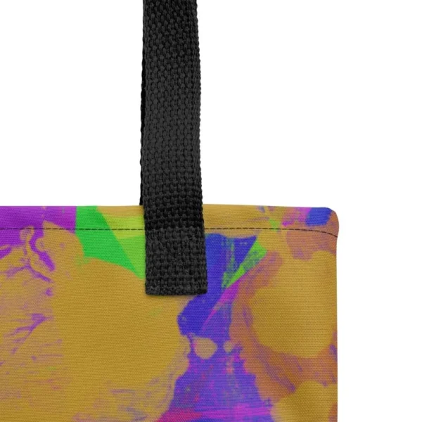 Close-up of the top corner of a Kaleidoscope Dream all-over print tote bag, showing the black handle and detailed stitching with the colourful abstract pattern in green, purple, yellow, blue and pink