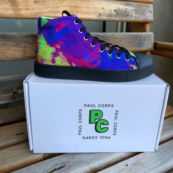 A pair of Paul Corps Kaleidoscope Dream High Top Canvas Shoes featuring a vibrant, abstract pattern in purple, blue, green, and orange, with black laces and black soles, displayed in front of a branded Paul Corps shoe box.