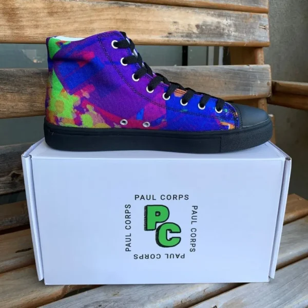A pair of Paul Corps Kaleidoscope Dream High Top Canvas Shoes featuring a vibrant, abstract pattern in purple, blue, green, and orange, with black laces and black soles, displayed in front of a branded Paul Corps shoe box.