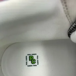 A pair of Paul Corps Kaleidoscope Dream High Top Canvas Shoes featuring a vibrant, abstract pattern in purple, blue, green, and orange, with black laces and black soles, displaying inside Branded Paul Corps logo