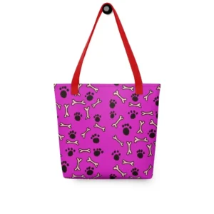 A Paul Corps large tote bag featuring a playful design of black paw prints and white bone motifs on a vibrant pink background, finished with sturdy black, red, yellow handles.