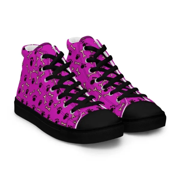 A pair of Paul Corps high-top canvas shoes with a vibrant pink background, decorated with black paw prints and white bone motifs, black laces, and black soles.