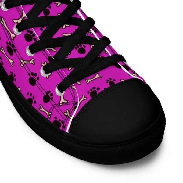 A pair of Paul Corps high-top canvas shoes with a vibrant pink background, decorated with black paw prints and white bone motifs, black laces, and black soles.