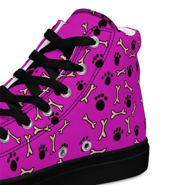 A pair of Paul Corps high-top canvas shoes with a vibrant pink background, decorated with black paw prints and white bone motifs, black laces, and black soles.