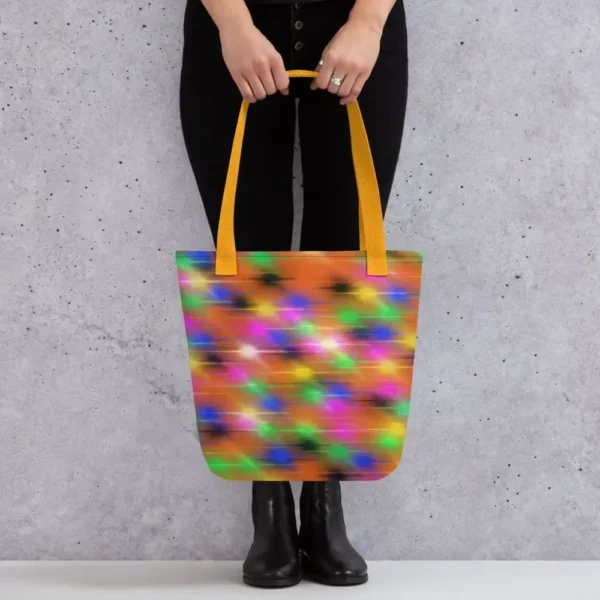 A Paul Corps large tote bag featuring a vibrant spray paint-inspired design with dynamic streaks of blue, pink, orange, and yellow on a black background, finished with sturdy black, red or yellow handles.