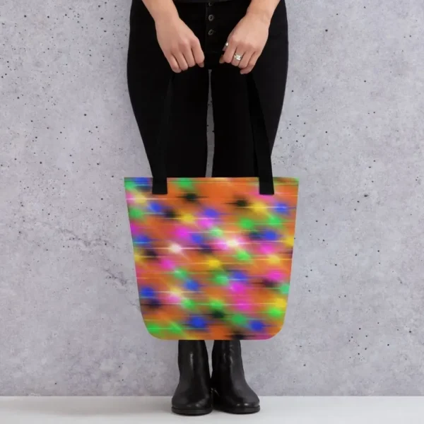 A Paul Corps large tote bag featuring a vibrant spray paint-inspired design with dynamic streaks of blue, pink, orange, and yellow on a black background, finished with sturdy black, red or yellow handles.