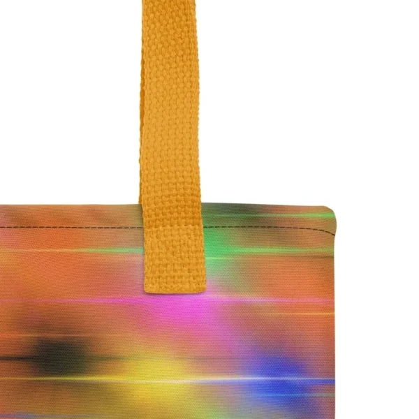 A Paul Corps large tote bag featuring a vibrant spray paint-inspired design with dynamic streaks of blue, pink, orange, and yellow on a black background, finished with sturdy black, red or yellow handles.
