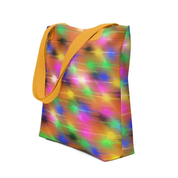 A Paul Corps large tote bag featuring a vibrant spray paint-inspired design with dynamic streaks of blue, pink, orange, and yellow on a black background, finished with sturdy black, red or yellow handles.