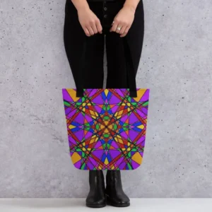 A person holding a Stain Glass Effect all-over print tote bag by the black handles, featuring a bold abstract pattern in green, purple, yellow, and pink, standing against a light speckled wall