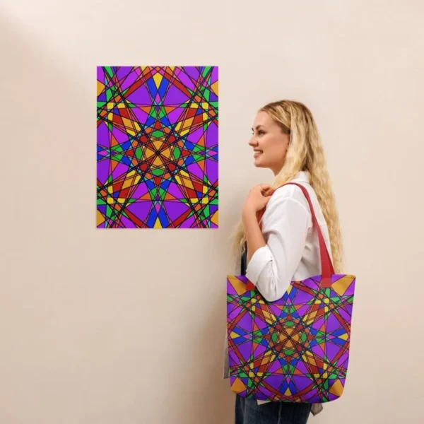 A person wearing a Stain Glass Effect all-over print tote bag with red handles over their shoulder, standing in front of a matching abstract art print on a beige wall