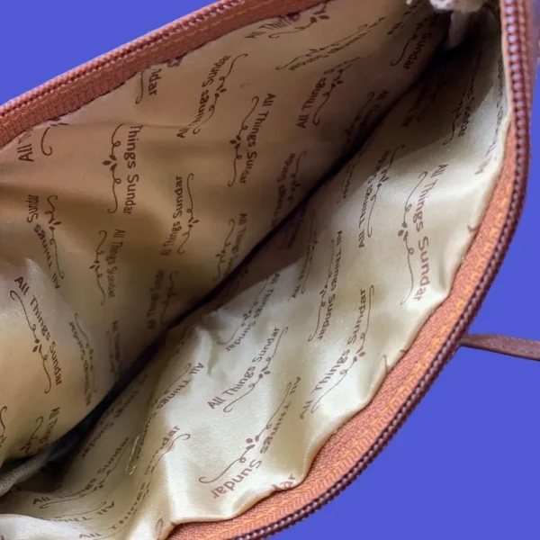 Inside view of pre-loved owl sling bag showing zippered main compartment and soft lining.